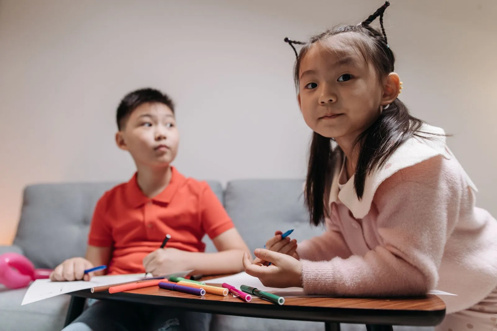 兩個亞洲孩子坐在桌邊用彩色筆畫畫