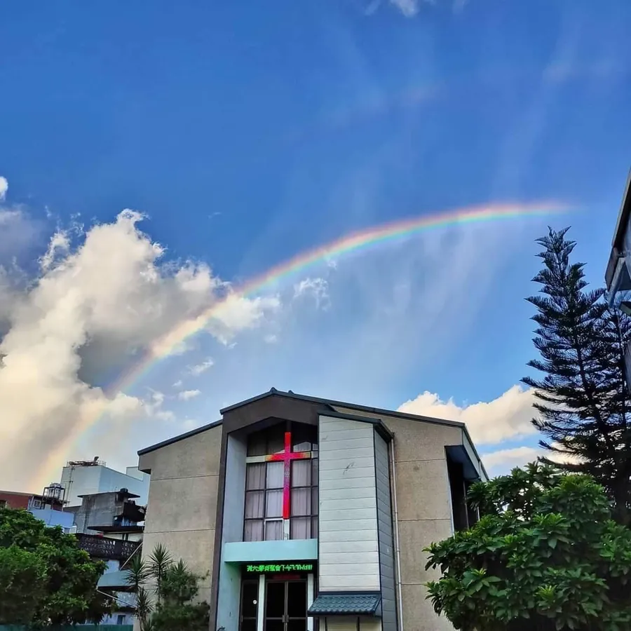 基督徒宜蘭禮拜堂外觀,建築正面有紅色十字架,上方藍天掛著一道彩虹
