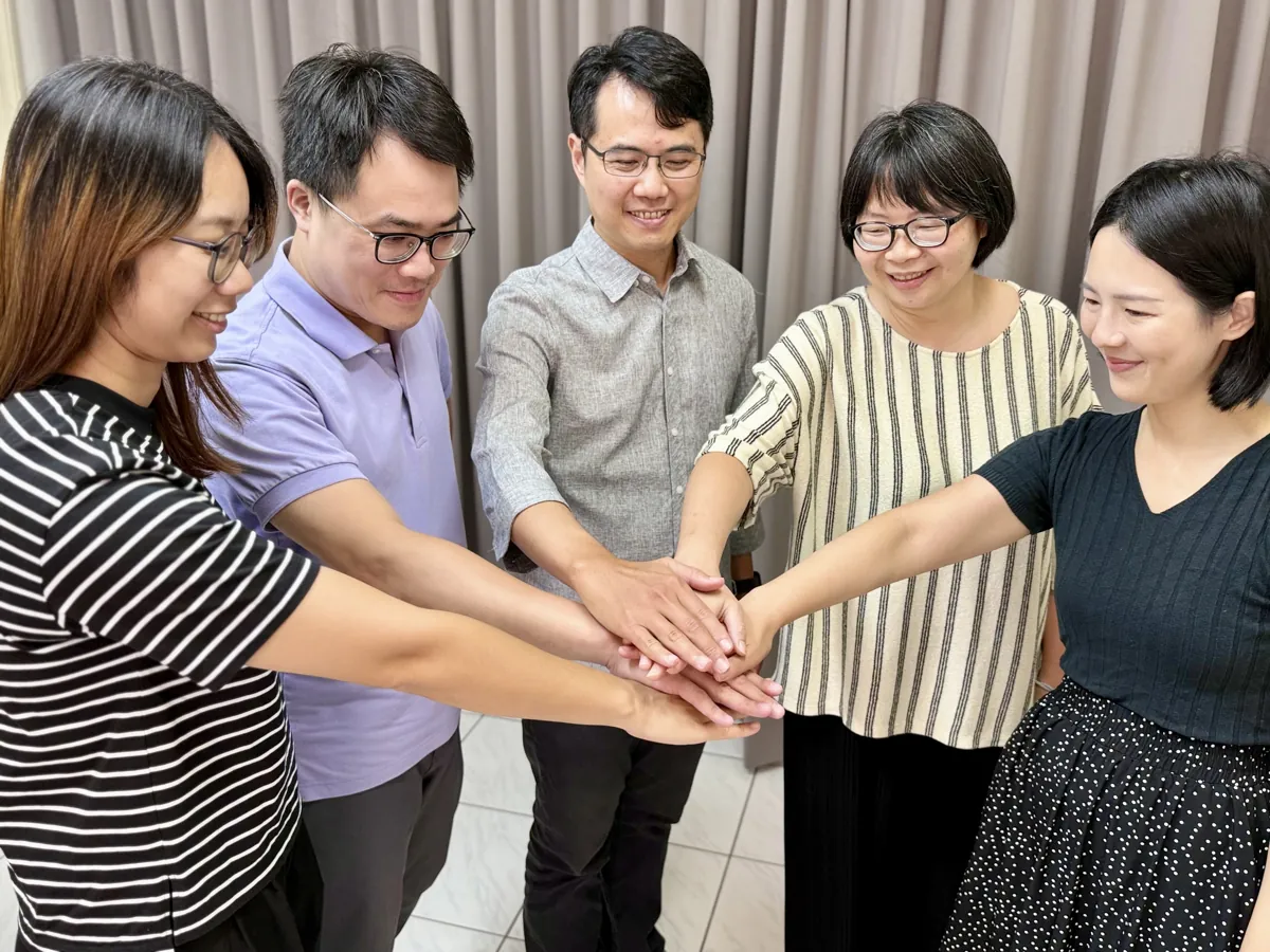 利河伯靈糧堂的弟兄姊妹圍成一圈，手疊在一起